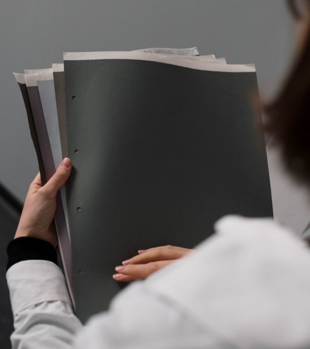 Close-up of a businesswoman holding and reviewing documents in an office setting.